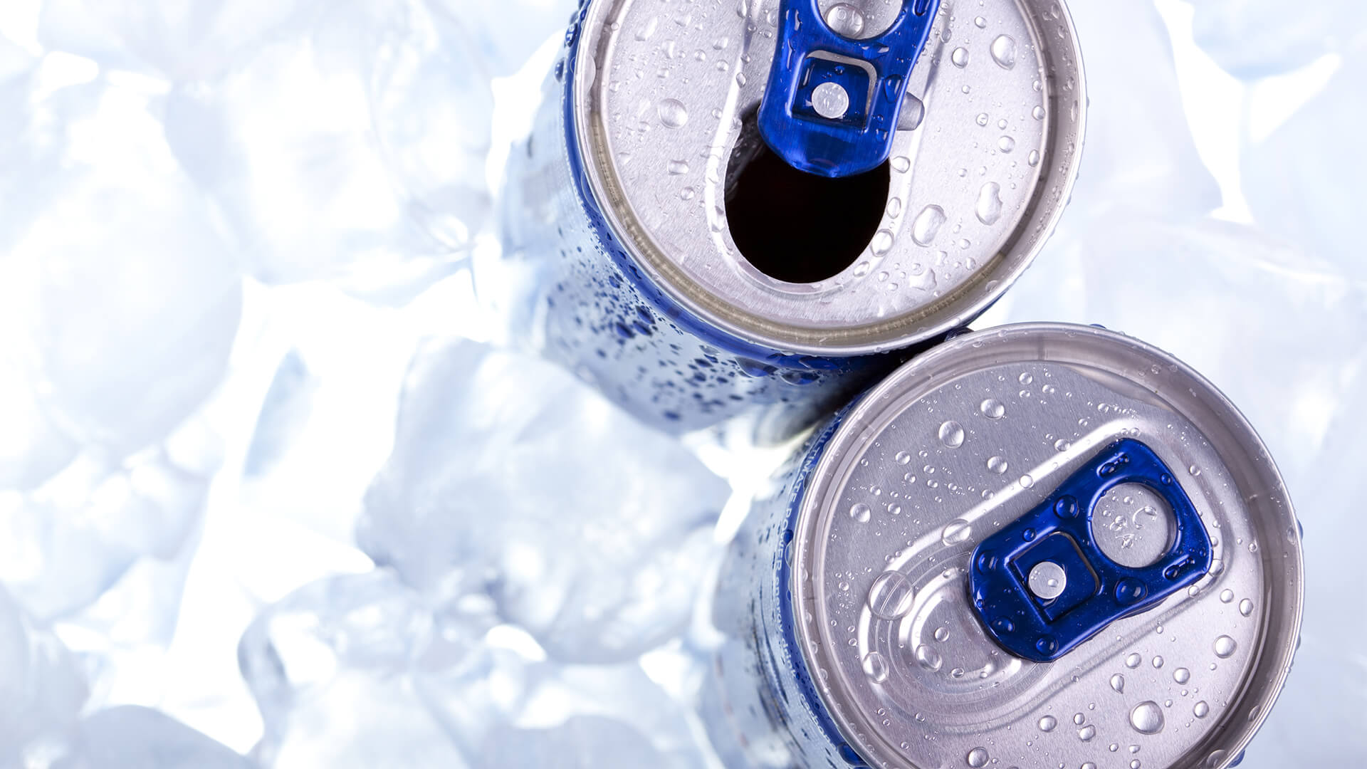 Open drink and closed drink cans with ring pulls, sitting in ice
