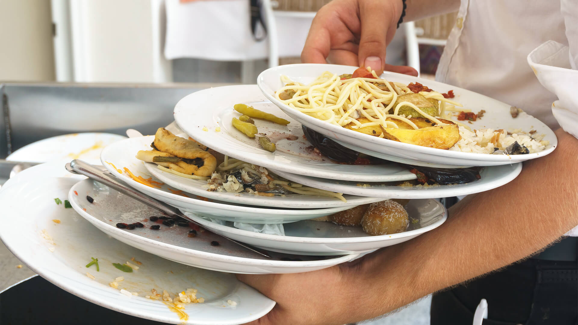 Waiter returning used plates to the kitchen with food remenants still on them