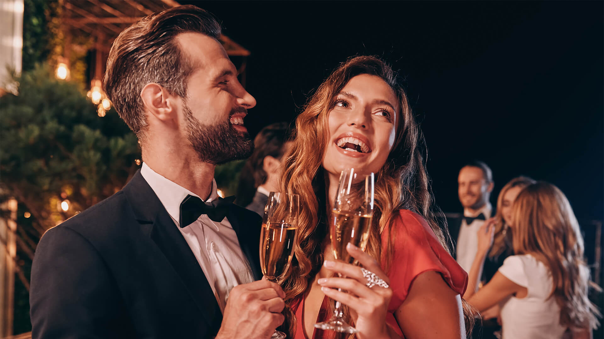 young couple in formalwear toasting with champagne while spending time on luxury party