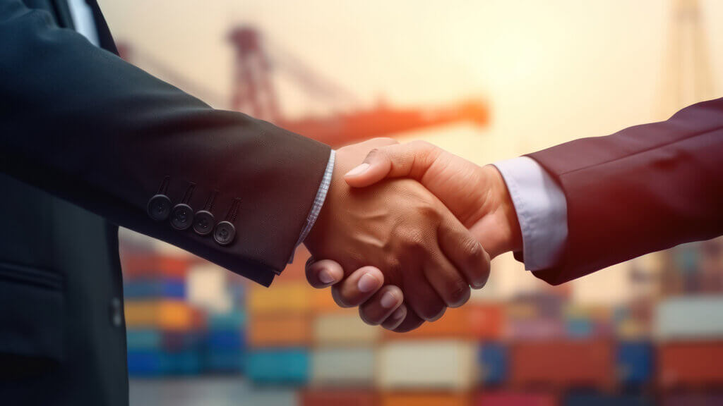 Handshake of two businessmen against the backdrop of a large container warehouse